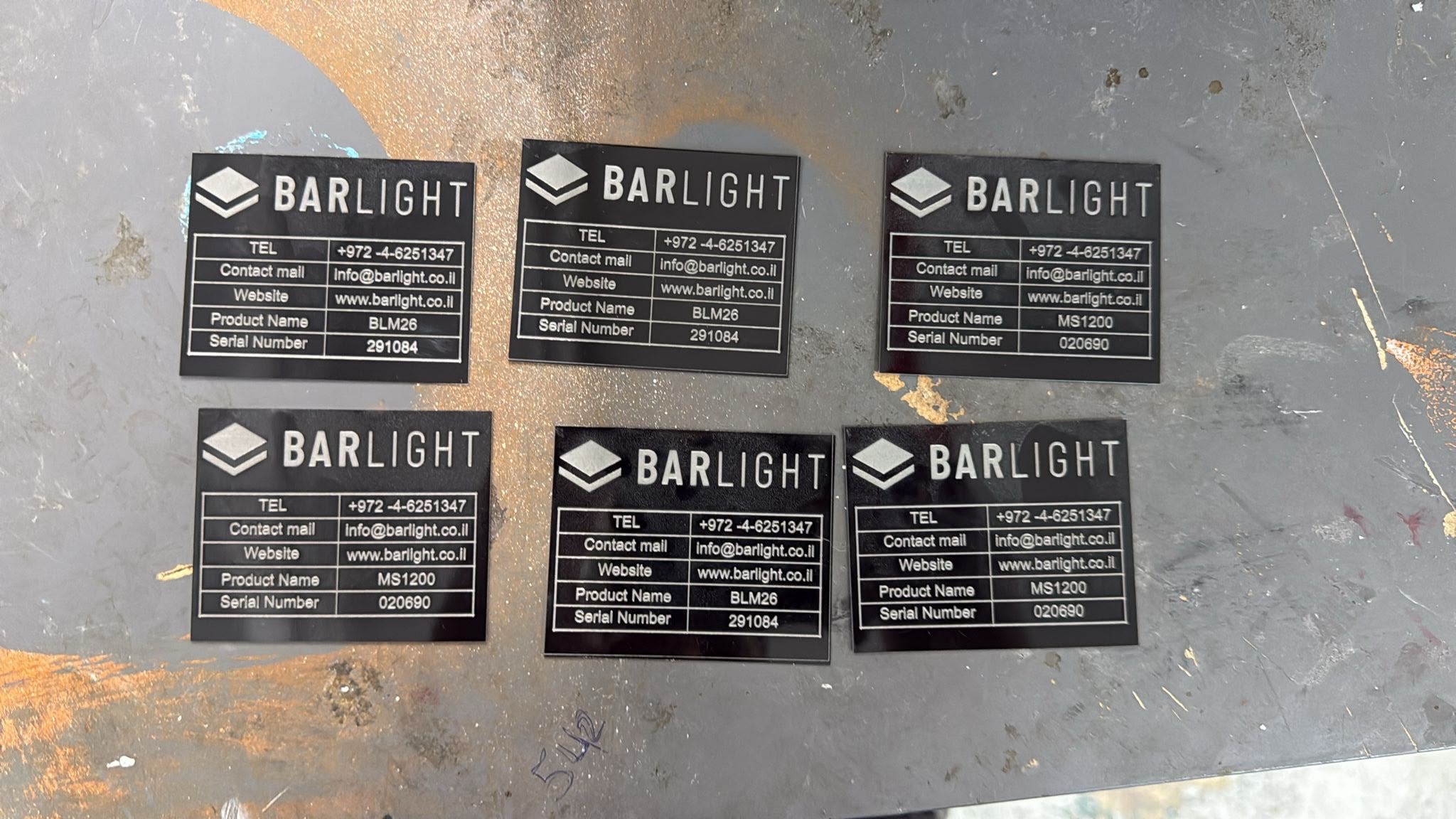 חריטה על לוחיות אלומיניום שחורות לחברת BARLIGHT דגמים BLM26 ו MS1200 עם מספרים סידוריים