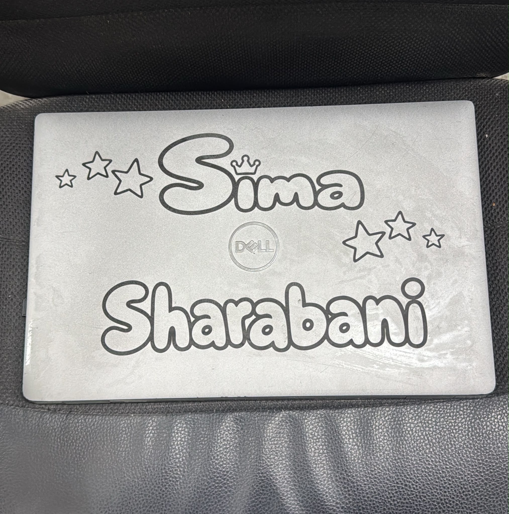 חריטה על מכסה לפטופ Dell עם השם Sima Sharabani ועיטור כתר וכוכבים