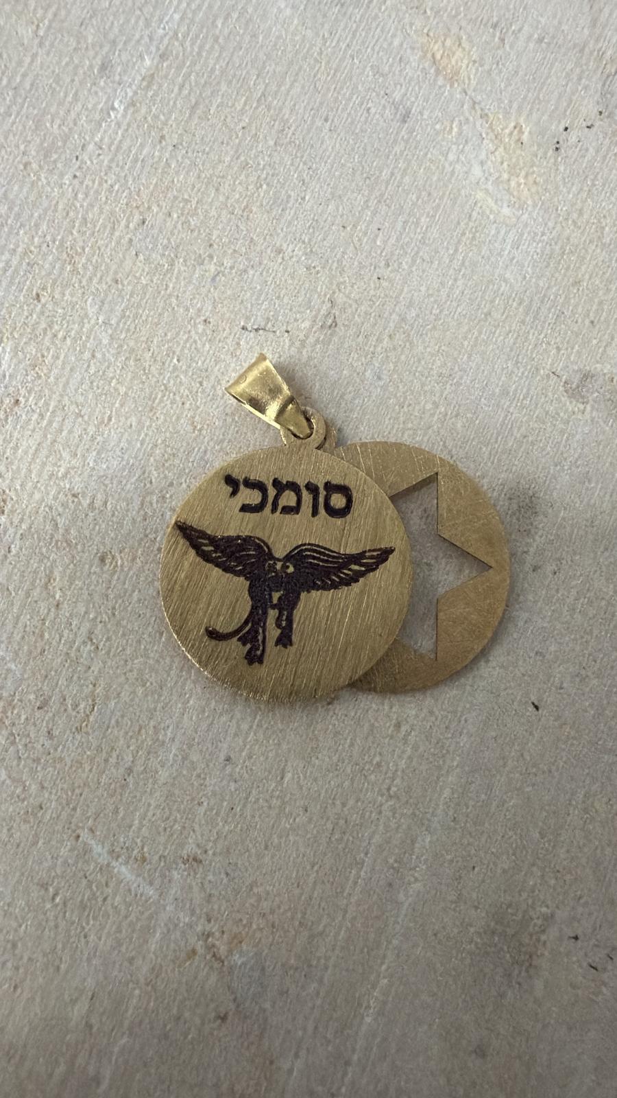 חריטה על תליון זהוב עם הכיתוב סומכי וציור נשר לצד תליון מגן דוד חתוך