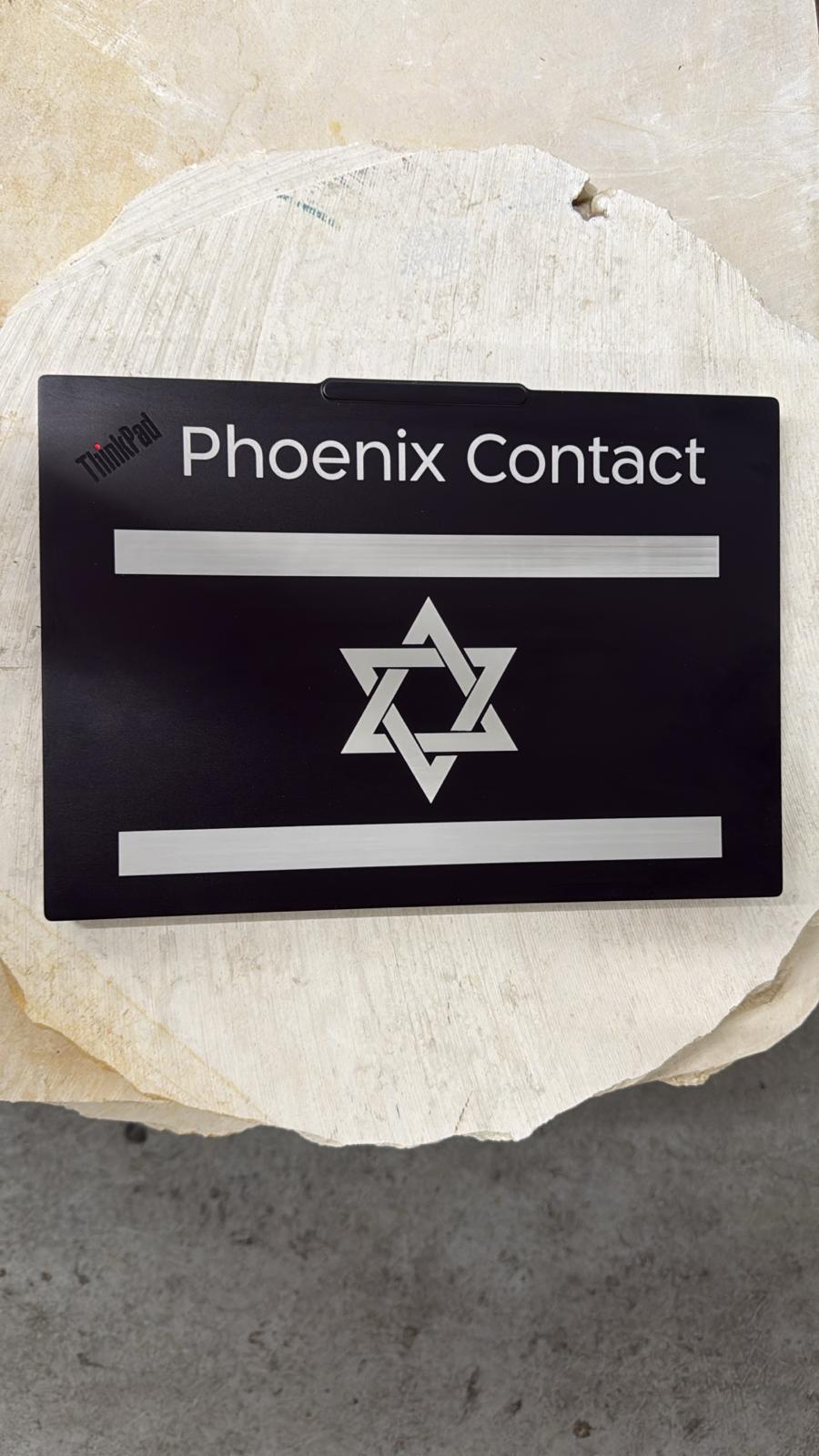 חריטת דגל ישראל על מכסה לפטופ ThinkPad שחור עם השם Phoenix Contact
