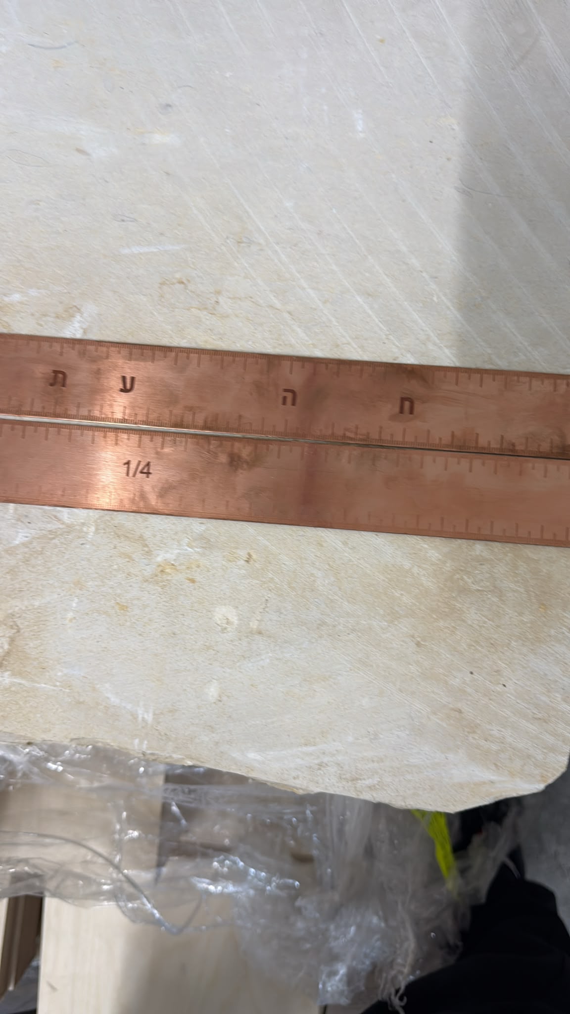 תקריב חריטת אותיות עבריות וסימוני מידה על פס נחושת