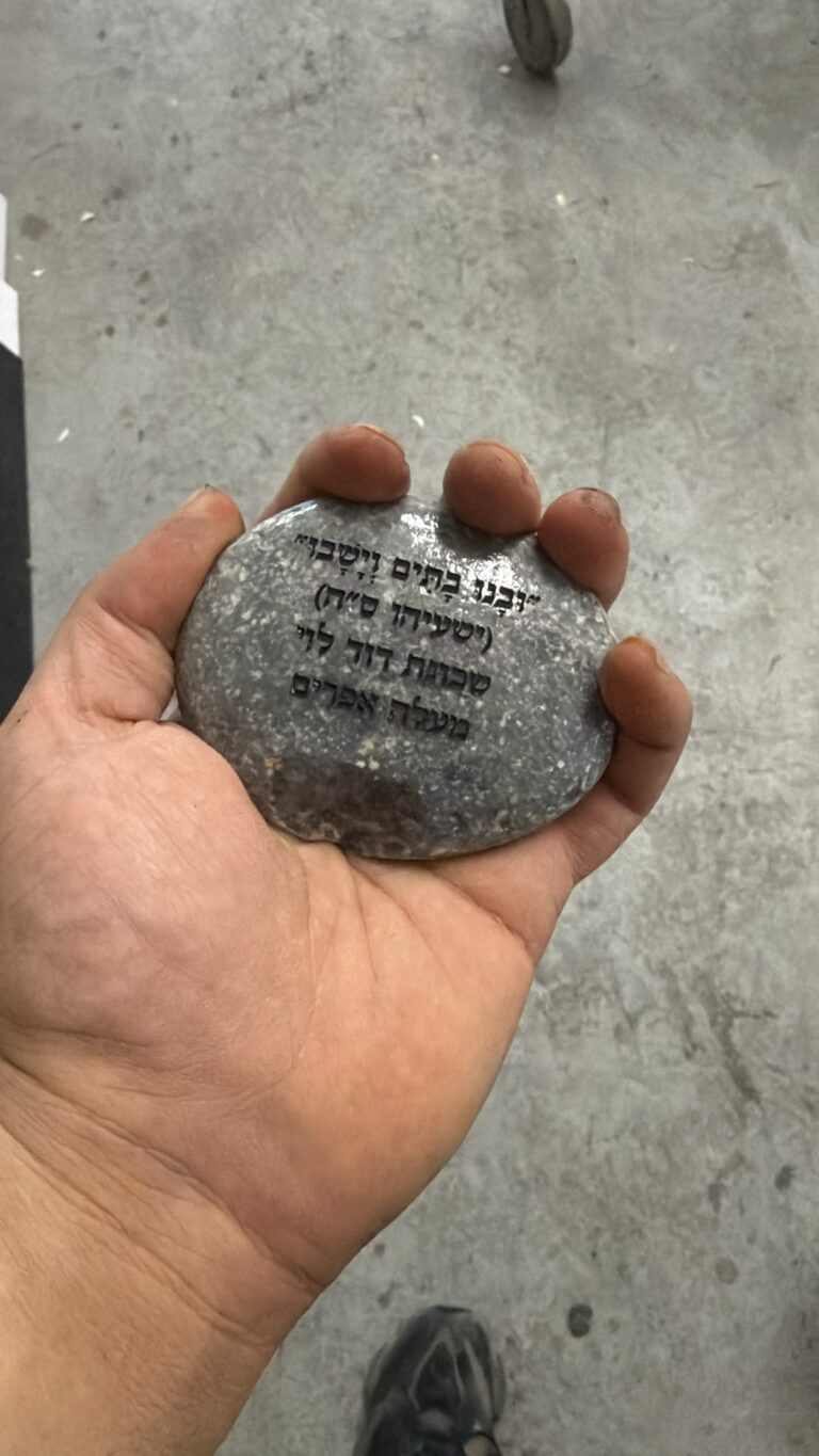 חלוק נחל מוחזק ביד עם חריטת ישעיהו סה לשכונת דוד לוי במעלה אפרים