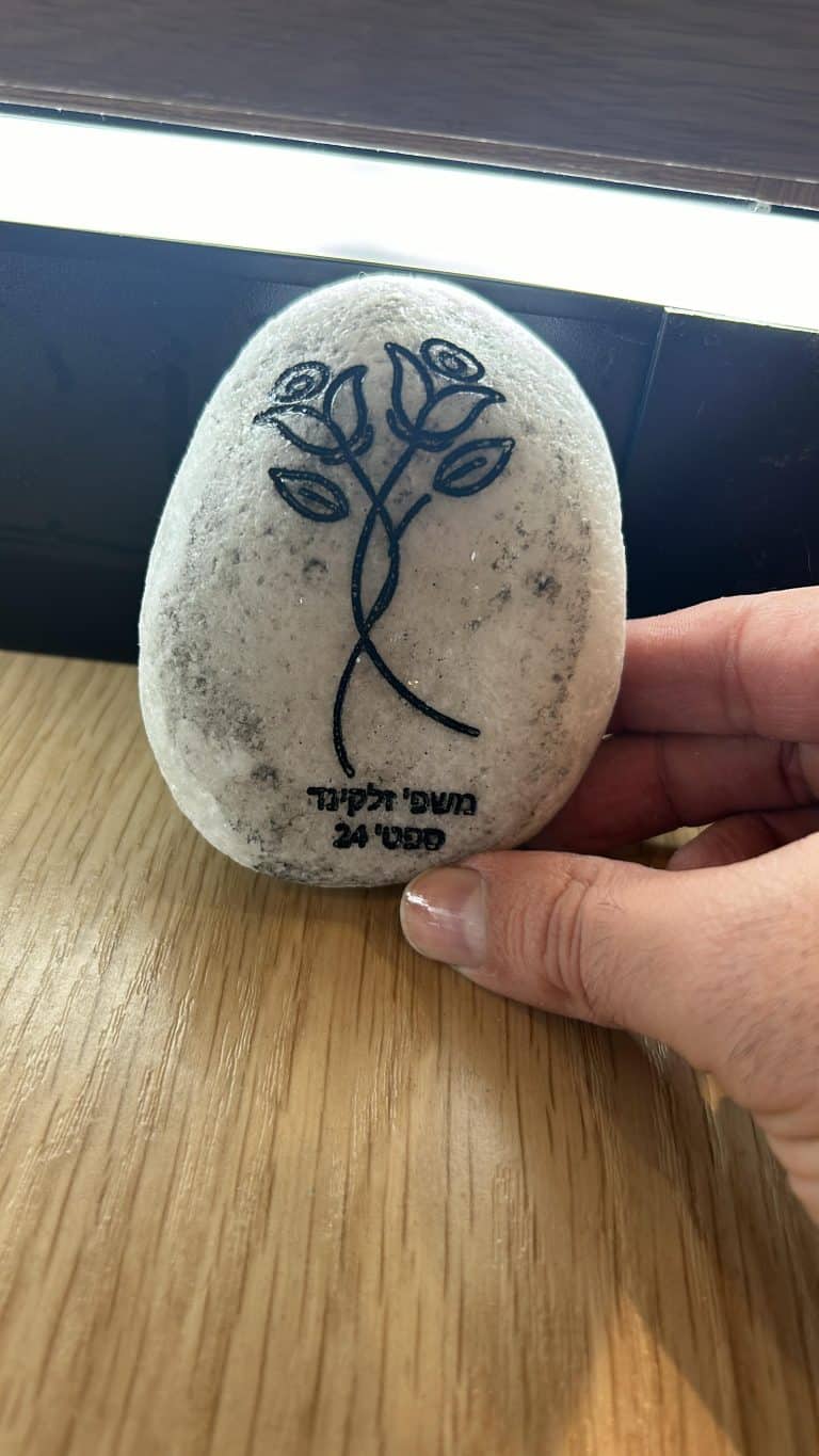 חריטה על זר פרחים על חלוק נחל לבן
