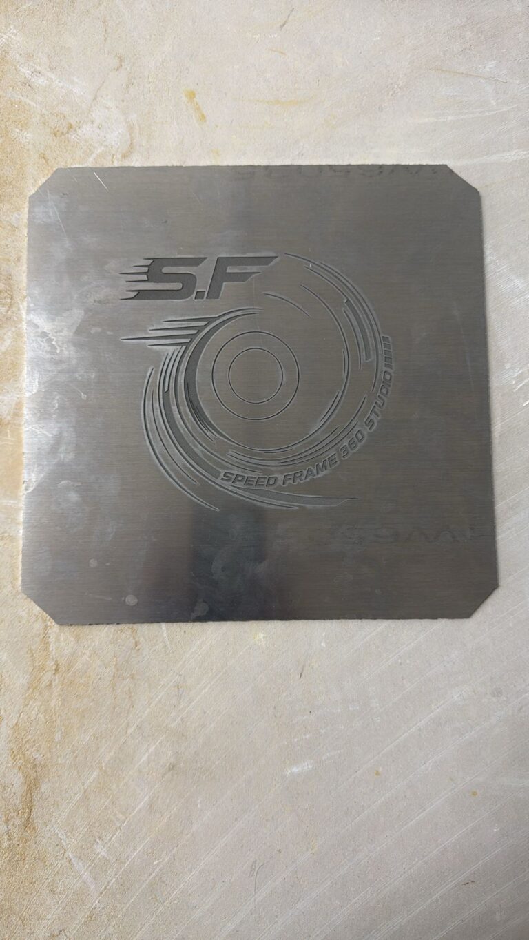 חריטה על לוחית מתכת כהה עם לוגו S.F Speed Frame 360 Studio
