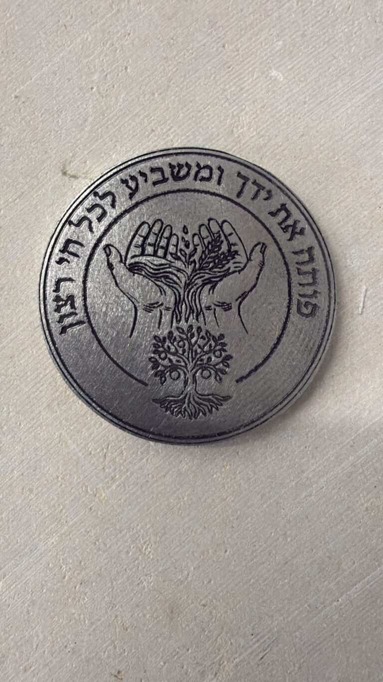 חריטה על מטבע מתכת עם כפיים פתוחות ועץ החיים והפסוק פותח את ידך ומשביע לכל חי רצון
