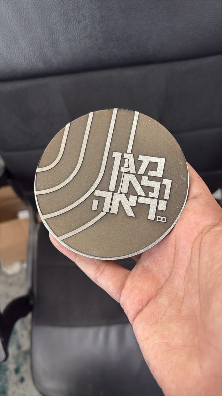 חריטה על מטבע מתכת עם קווים מעוגלים והכיתוב בגאון ובאהבה