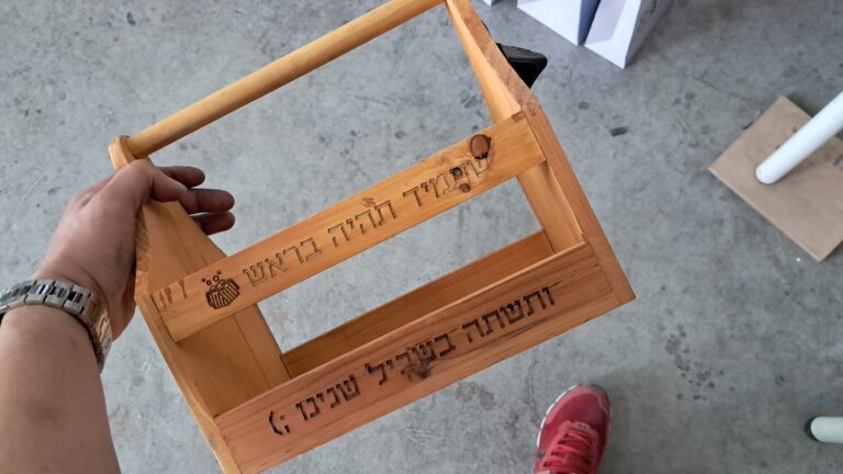 חריטה על מנשא בירות עץ עם כיתוב עברי ולוגו משושה חרוט