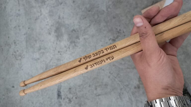 חריטה על מקלות תופים מעץ לעדן ויטרוב עם הכיתוב תמיד בקצב שלך ולבבות