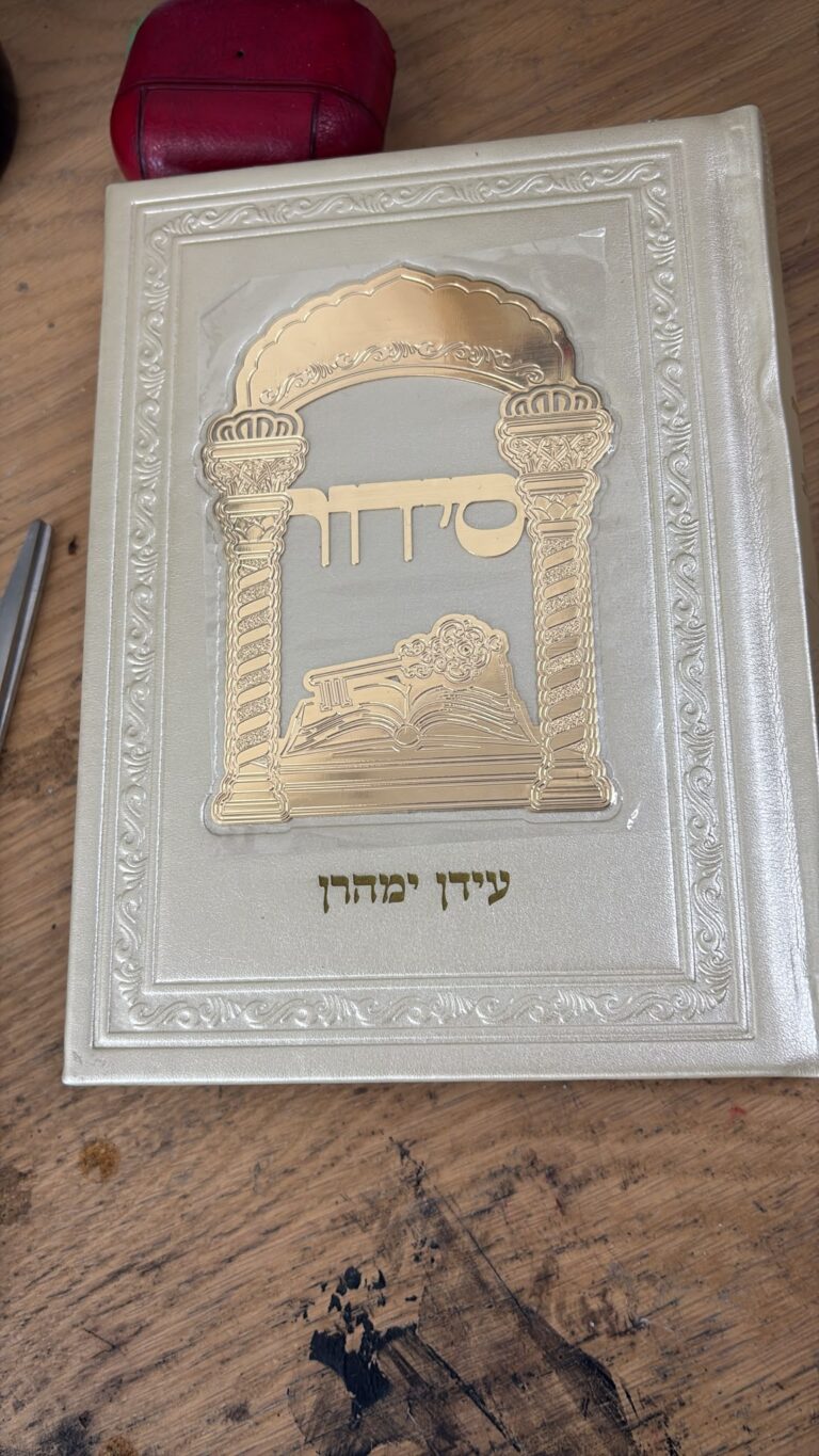 חריטה על סידור מהודר בכריכה לבנה עם השם עיידן ימהרן