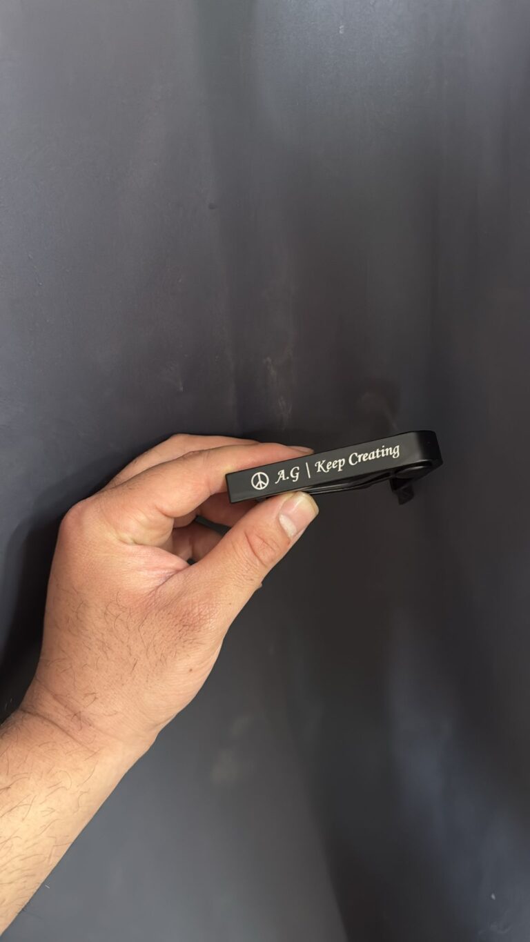 חריטה על קאפו לגיטרה מתכת שחור עם סמל שלום והכיתוב A.G Keep Creating
