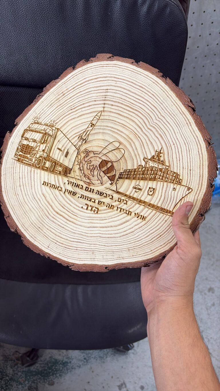 חריטה של אוניית מכולות משאית טיל ודבורה על פרוסת גזע עץ עם הכיתוב בים ביבשה וגם באוויר