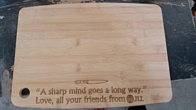 חריטה של המשפט A sharp mind goes a long way ולוגו JLL על קרש חיתוך במבוק