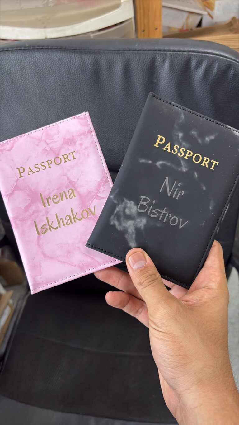 חריטה של השמות Irena Iskhakov ו Nir Bistrov על שני כיסויים לדרכון בהדפס שיש ורוד ושחור