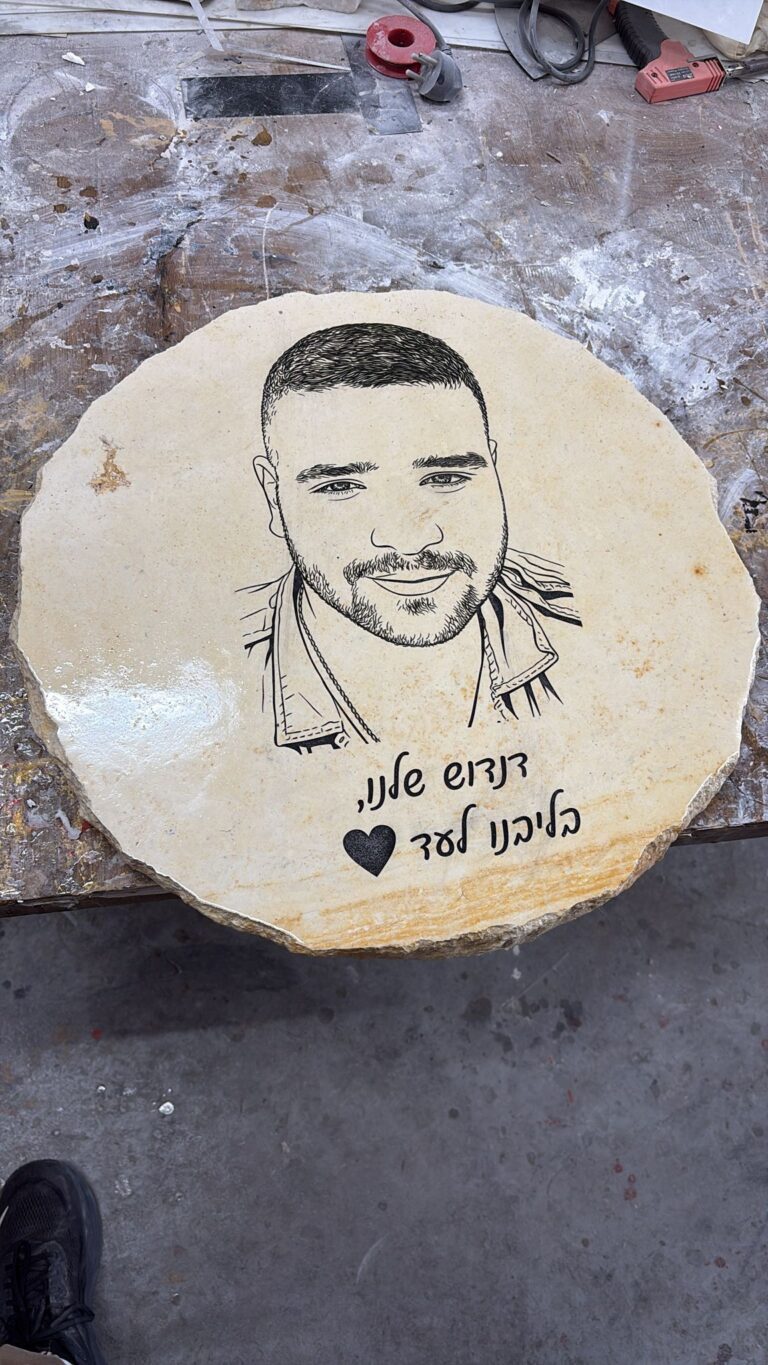 חריטה של פורטרט גבר ופסוק לזכר דניאל על אבן להנצחה עגולה
