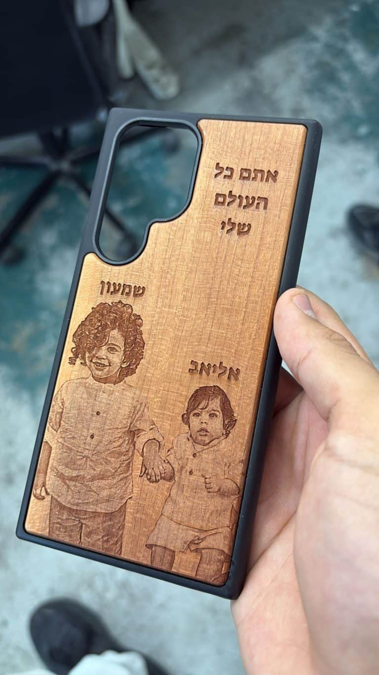 חריטה של שני ילדים על מגן לטלפון מעץ