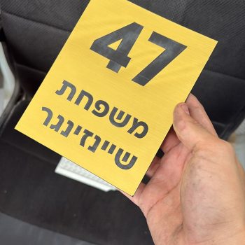 לוחית זהב עם חריטה של מספר דירה ושם משפחה
