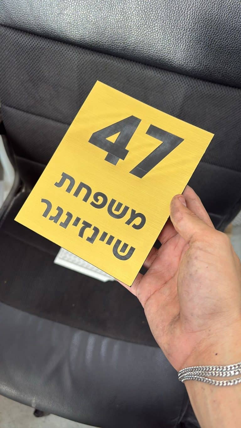 לוחית זהב עם חריטה של מספר דירה ושם משפחה