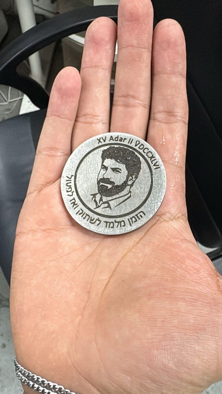 מטבע מתכת עם חריטה דיוקן פנים וכיתוב ביוונית