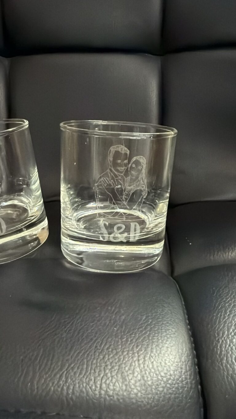 תקריב חריטת דיוקן חתן וכלה על כוס וויסקי מזכוכית
